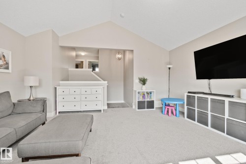 Vaulted ceiling, neutral wall paint, carpeted flooring, upper-level hallway, and a contemporary light fixture - 2096 Redtail Common Nw, Edmonton, AB 