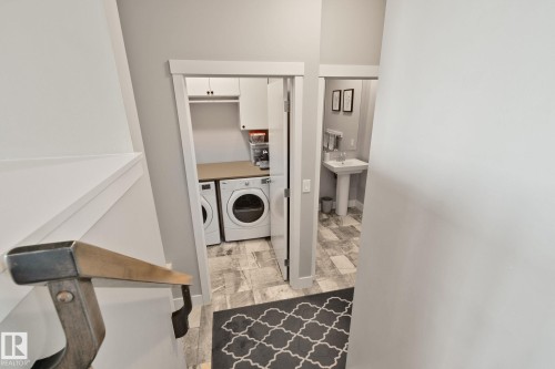 Laundry area with front-load washer and dryer, built-in cabinetry, and countertop - 2096 Redtail Common Nw, Edmonton, AB 