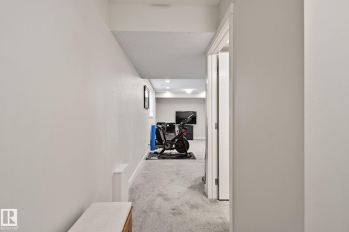 Carpeted hallway with recessed lighting and a white paneled door frame - 2096 Redtail Common Nw, Edmonton, AB 