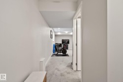 Carpeted hallway with recessed lighting and a white paneled door frame - 