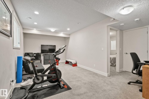 Light gray carpeting throughout a versatile room with recessed lighting and a window - 2096 Redtail Common Nw, Edmonton, AB 