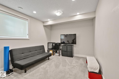 Carpeted room featuring a window with roller blinds, recessed lighting, and a built-in media niche - 2096 Redtail Common Nw, Edmonton, AB 