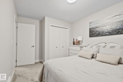 Neutral wall tones, textured ceiling, light-toned carpet flooring, white bi-fold closet doors, and a flush-mount ceiling light fixture - 