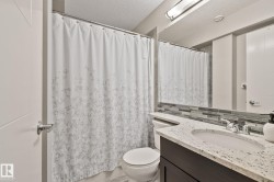 Bathroom featuring a vanity with an integrated sink, polished chrome faucet, and a stone-finish countertop - 