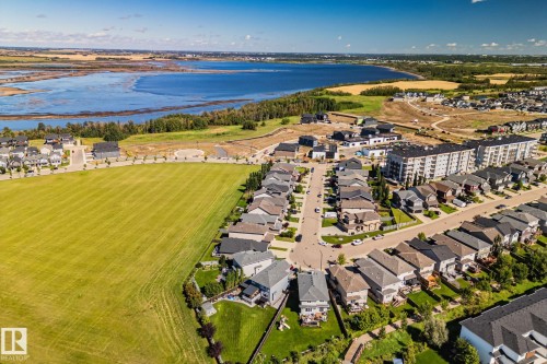 Expansive green space bordering a residential community with a large body of water and natural landscape in the background - 2096 Redtail Common Nw, Edmonton, AB 
