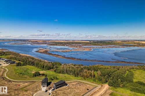 Waterfront landscape with a residential development featuring newly constructed homes, natural green spaces, and a winding waterway - 2096 Redtail Common Nw, Edmonton, AB 