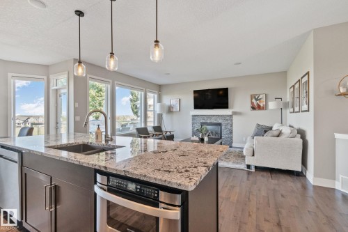 Spacious kitchen island with granite countertops, stainless steel appliances, and pendant lighting - 2096 Redtail Common Nw, Edmonton, AB 