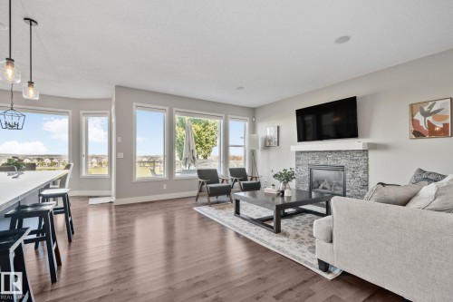 Bright, open-concept living area featuring expansive multi-pane glass doors and windows flooding the space with natural light - 2096 Redtail Common Nw, Edmonton, AB 