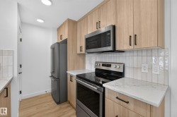 Wood-finish cabinetry paired with light countertops, stainless steel appliances, and a tiled backsplash - 