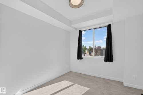 Room featuring light gray walls, plush carpeting, a large window, and a flush mount ceiling light - #58 16231 19 Av Sw, Edmonton, AB 