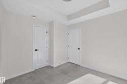 Recessed ceiling lighting, tray ceiling, neutral wall color, contemporary interior doors with black hardware, and grey carpeting - 