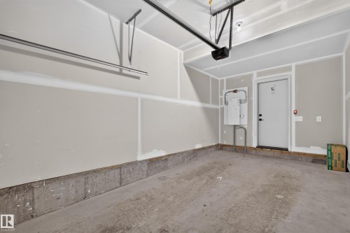 Attached garage with concrete flooring, drywall walls, and an overhead garage door opener - #58 16231 19 Av Sw, Edmonton, AB 