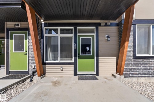 Modern exterior featuring contrasting siding, dark brickwork, and a vibrant lime green entry door - #58 16231 19 Av Sw, Edmonton, AB 