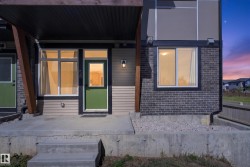 Modern exterior with a green entry door, concrete patio, dark brick accents, and horizontal siding - 