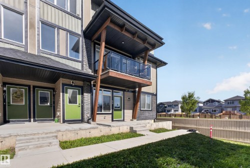 Contemporary multi-story exterior with a balcony featuring a glass railing and wood supports - #58 16231 19 Av Sw, Edmonton, AB 