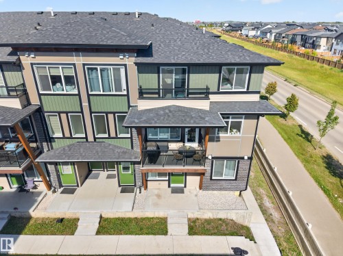 Multi-level exterior with a prominent balcony, asphalt shingle roofing, and a front patio - #58 16231 19 Av Sw, Edmonton, AB 