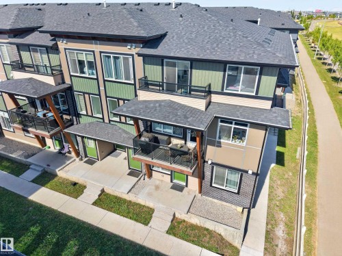 Multi-story exterior featuring balconies with glass railings, covered entrances, and varied siding materials - #58 16231 19 Av Sw, Edmonton, AB 