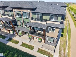 Multi-story exterior featuring balconies with glass railings, covered entrances, and varied siding materials - 
