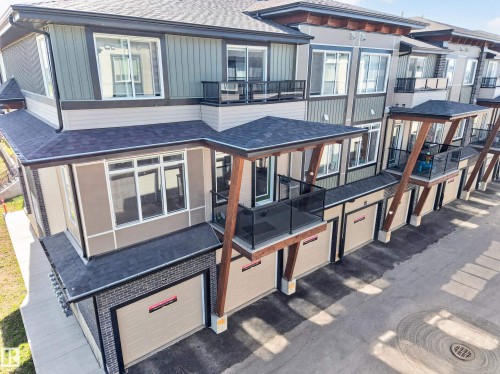 Contemporary townhome exterior featuring multi-toned siding, attached garages, private balconies with glass railings, and a shingled roof - #58 16231 19 Av Sw, Edmonton, AB 