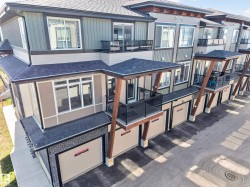 Contemporary townhome exterior featuring multi-toned siding, attached garages, private balconies with glass railings, and a shingled roof - 