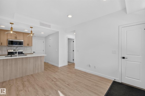 Kitchen with wood-finish cabinetry, stainless steel appliances, and a tile backsplash - #58 16231 19 Av Sw, Edmonton, AB 