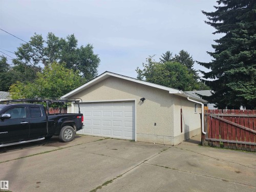 Detached garage with a paneled door, exterior lighting, and a concrete driveway - 12130 124 Street Nw, Edmonton, AB 