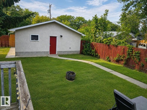 Expansive green lawn, a dedicated concrete pathway, and a detached structure with a red entry door and a white window - 12130 124 Street Nw, Edmonton, AB 