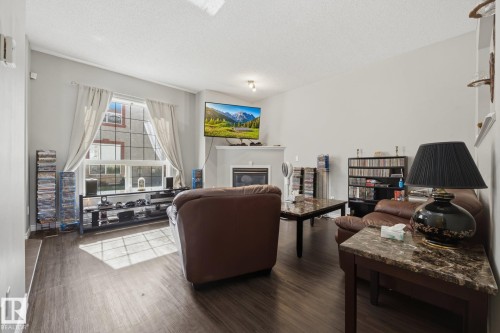 Vaulted ceiling, wood-finish flooring, large multi-pane window, integrated fireplace, and a mantel - #102 13825 155 Av Nw, Edmonton, AB 