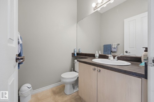 Recessed lighting fixture, light gray walls, vanity with wood-finish cabinetry, dark countertop, and integrated white sink, ceramic tile flooring - #102 13825 155 Av Nw, Edmonton, AB 