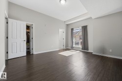 Tray ceiling detail, dark wood-finish flooring, white trim, window with natural light, and a built-in closet - 