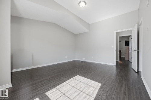 Spacious room featuring wood-finish flooring, light gray walls, white trim, and a ceiling-mounted light fixture - #102 13825 155 Av Nw, Edmonton, AB 