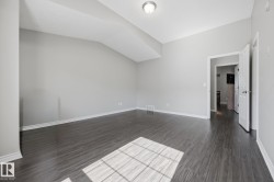Spacious room featuring wood-finish flooring, light gray walls, white trim, and a ceiling-mounted light fixture - 