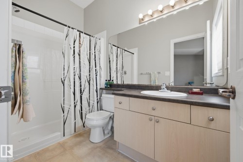 Single-basin vanity with ample counter space, integrated mirror, and overhead lighting - #102 13825 155 Av Nw, Edmonton, AB 