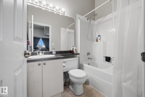 Vanity with integrated sink, dark countertop, and storage cabinetry - #102 13825 155 Av Nw, Edmonton, AB 