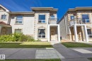 Stucco exterior with stone accents, arched windows, and a second-story balcony with metal railing - #102 13825 155 Av Nw, Edmonton, AB 