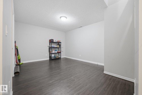Spacious room featuring wood-finish flooring, light grey walls, and a recessed ceiling light fixture - #102 13825 155 Av Nw, Edmonton, AB 