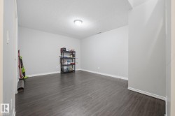Spacious room featuring wood-finish flooring, light grey walls, and a recessed ceiling light fixture - 