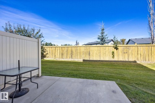 Expansive backyard featuring a concrete patio, a manicured lawn, and a wood privacy fence - #102 13825 155 Av Nw, Edmonton, AB 