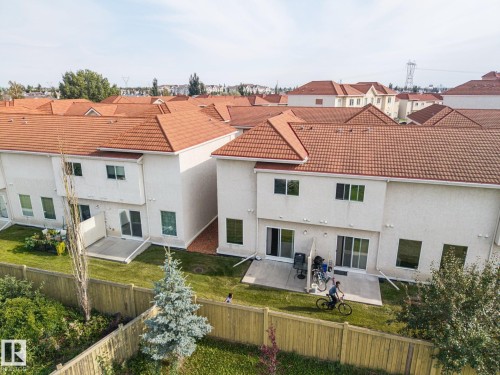 Terracotta tile roof, stucco exterior, rear patio, and a fenced yard - #102 13825 155 Av Nw, Edmonton, AB 