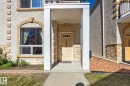 Stucco exterior with stone accents, arched window and doorway details, covered entry, and paved walkway - #102 13825 155 Av Nw, Edmonton, AB 