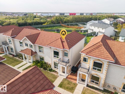 Stucco exterior with stone accents, red tile roofing, and multiple balconies - #102 13825 155 Av Nw, Edmonton, AB 