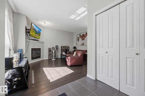 Living area featuring a fireplace with a mantel, dark wood-finish flooring, and a vaulted ceiling - #102 13825 155 Av Nw, Edmonton, AB 
