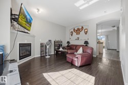 Vaulted ceiling with track lighting, wood-finish flooring, and a fireplace with a mantel - 