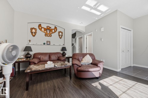 Archway wall feature, wood-finish flooring, light grey wall paint, white trim, bi-fold closet door - #102 13825 155 Av Nw, Edmonton, AB 
