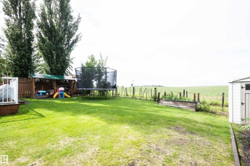 Expansive green lawn with a wooden privacy fence - 5502 60 Avenue, Barrhead, AB - Outdoor