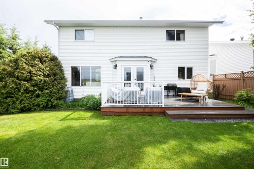 Expansive rear yard featuring a multi-level wood deck with white railings, a stone patio, and a large green lawn - 5502 60 Avenue, Barrhead, AB - Outdoor With Deck Patio Veranda