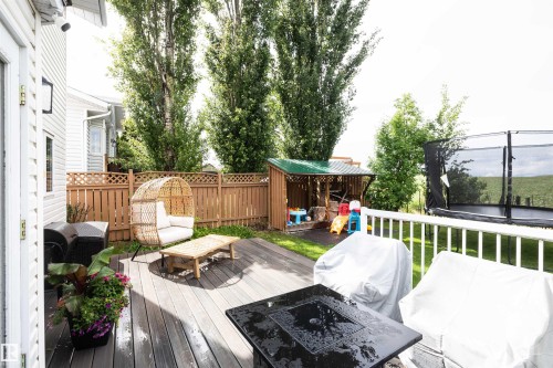 Spacious wood-finish composite deck with white railing, privacy fence, and a dedicated play structure - 5502 60 Avenue, Barrhead, AB - Outdoor With Deck Patio Veranda