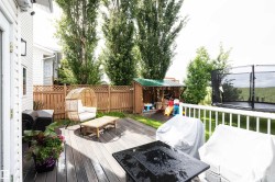 Spacious wood-finish composite deck with white railing, privacy fence, and a dedicated play structure - 