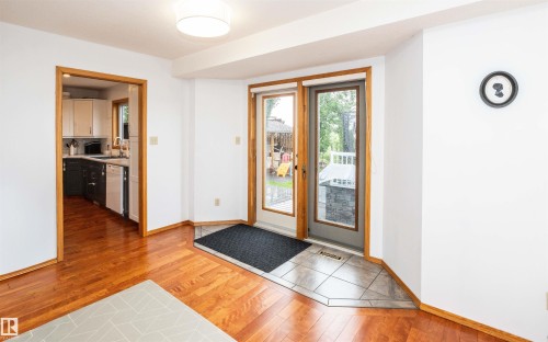 Hardwood flooring extends from the main area towards a doorway with a full light door featuring a tile landing - 5502 60 Avenue, Barrhead, AB - Indoor Photo Showing Other Room