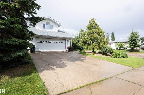 White vinyl siding exterior with an attached two-car garage featuring decorative window inserts - 5502 60 Avenue, Barrhead, AB - Outdoor